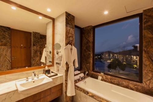 La salle de bains est pourvue d'une baignoire, d'un lavabo et d'une fenêtre. dans l'établissement Lemon Tree Premier, Corbett, à Garjia