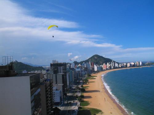 a kite flying over a beach next to the ocean at Flat praia Vila Velha ES in Vila Velha