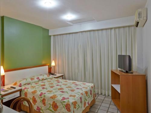 a hotel room with a bed and a tv at Flat praia Vila Velha ES in Vila Velha