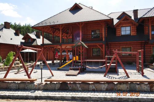 un parque infantil frente a una cabaña de madera en Oberza Knieja, en Raducki Folwark