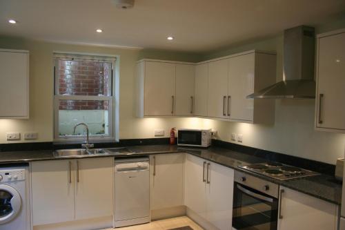a kitchen with white cabinets and a sink at Highlands Apartment 5 in Shanklin