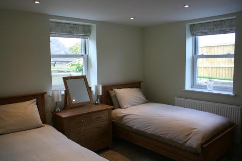 a bedroom with two beds and a mirror and two windows at Highlands Apartment 5 in Shanklin