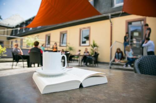 a cup of coffee and a book on a table at Jugendhaus St. Kilian in Miltenberg