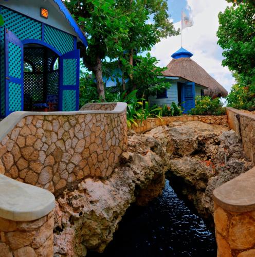 a bridge over a river in front of a house at The Caves in Negril