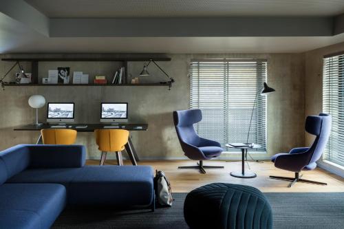 a living room with a blue couch and chairs at OKKO Hotels Strasbourg Centre in Strasbourg