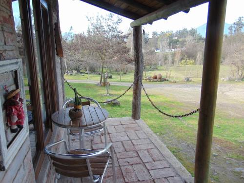 a porch with a table and two chairs and a swing at Cabañas Puente Negro in Puente Negro