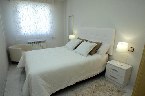 モリーノス・デ・ドゥエロにあるApartamento junto al Duero en la Sierra de Urbiónの白いベッドルーム(白いベッド1台、椅子付)