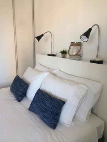 a white bed with two blue pillows and two lamps at Aveiro Panoramic in Aveiro