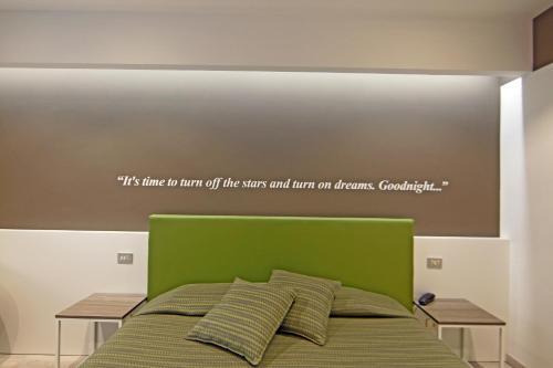 a bed with a green headboard with a quote on it at Hotel Ideal in Sirmione