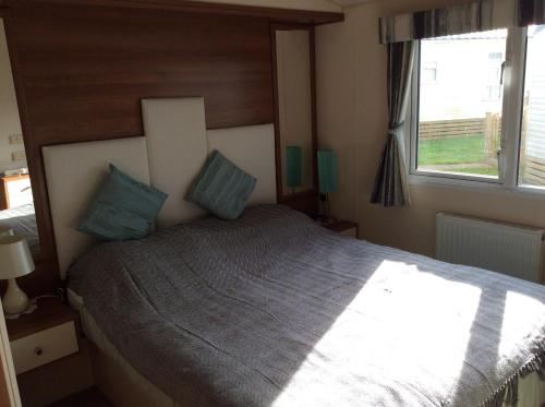 Un dormitorio con una cama con almohadas azules y una ventana en Warren View en Dawlish