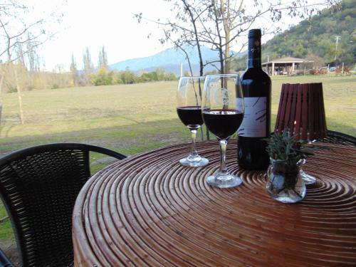two glasses of wine on a table with a bottle of wine at Cabañas Puente Negro in Puente Negro