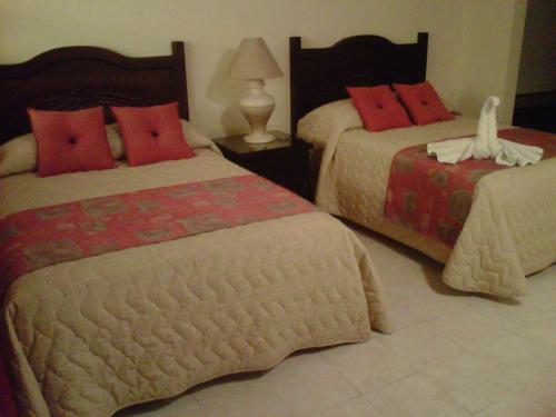 a bedroom with two beds with red pillows at Hotel Zaci in Valladolid