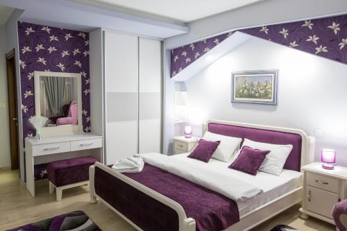een slaapkamer met een groot bed en een paarse muur bij Apartmani MG in Nikšić