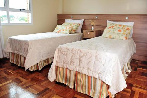 two beds sitting next to each other in a bedroom at Hotel Princesa dos Vales in Veranópolis