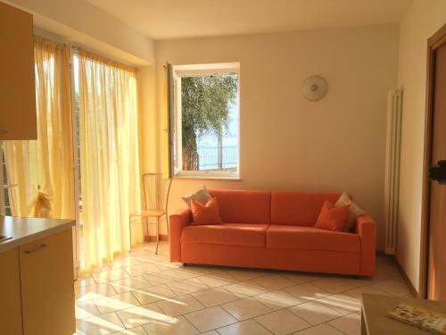 a living room with an orange couch and a window at Mary Apartments in Brenzone sul Garda