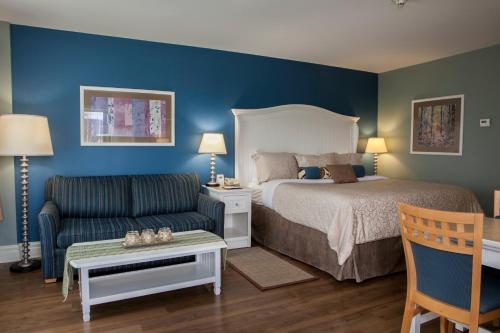 a bedroom with a bed and a couch and a chair at Watkins Glen Harbor Hotel in Watkins Glen