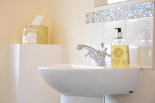a bathroom with a sink and a bottle of soap at The Dolphin Inn in Thorpeness