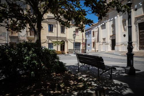 a park bench sitting on a sidewalk next to a street at Piazza San Pantaleo in Sorso