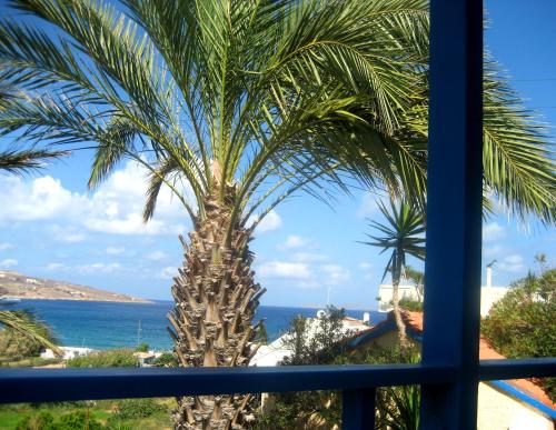 a palm tree looking out a window at the ocean at Corina Apartments in Sitia