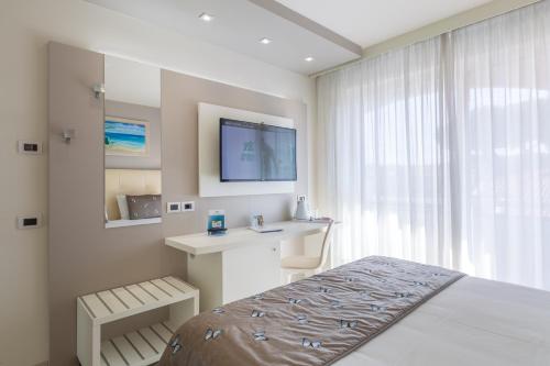 1 dormitorio con 1 cama, escritorio y TV en Hotel Eden, en Cinquale