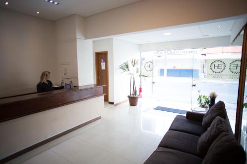 a woman sitting at a counter in a lobby at Hotel Embaixador in Cruzeiro