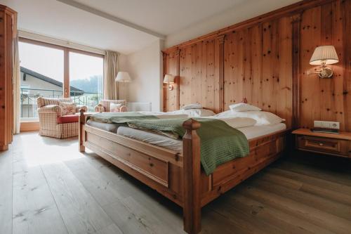 a bedroom with a large bed with a wooden wall at DER GREIL - Wein & Gourmethotel in Söll