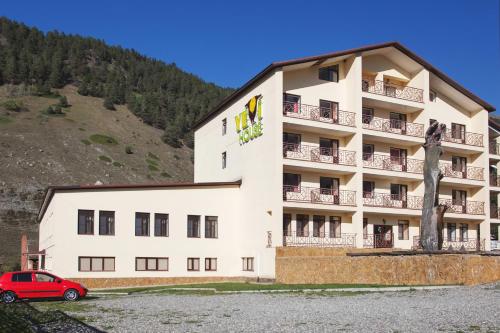 a hotel with a red car parked in front of it at Yetihouse in Teberda