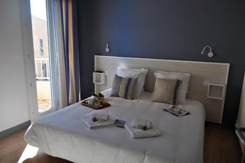 a bedroom with a white bed with two towels on it at Hôtel de la Mer in Valras-Plage