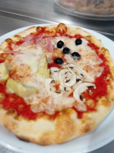 a pizza sitting on top of a white plate at Nido delle Rondini hotel Ristorante Pizzeria in Fallo