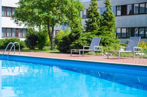a swimming pool with two lounge chairs next to a building at Novotel Poznań Malta in Poznań