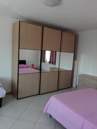 カルダーノ・アル・カンポにあるAppartamento Ormeniのベッドルーム1室(鏡付きの大きな木製キャビネット付)