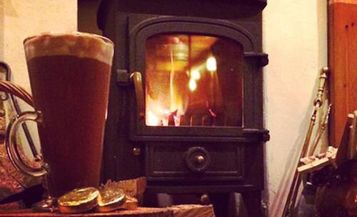 a fireplace with a glass of beer in front of it at The Badger Inn in Carbis Bay
