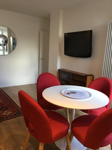 una camera con tavolo, sedie rosse e TV di Midtown London Apartment a Londra
