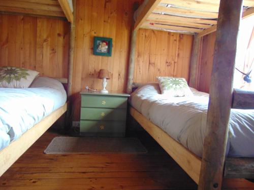 a bedroom with two beds in a log cabin at Cabañas Puente Negro in Puente Negro