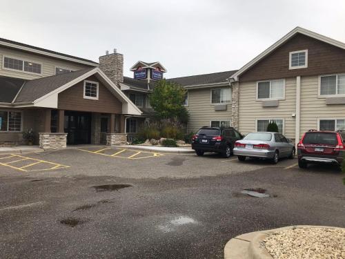 a parking lot with cars parked in front of a building at AmericInn by Wyndham Hotel and Suites Long Lake in Long Lake