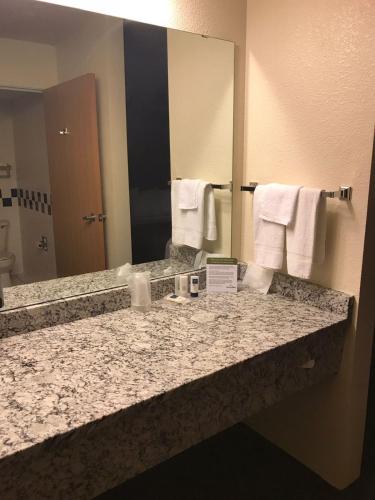 a bathroom with a granite counter top and a large mirror at AmericInn by Wyndham Hotel and Suites Long Lake in Long Lake