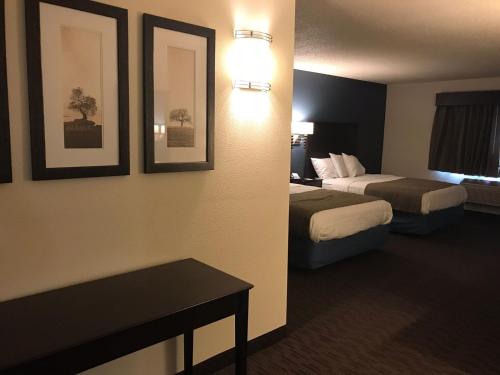 a hotel room with two beds and a table at AmericInn by Wyndham Hotel and Suites Long Lake in Long Lake