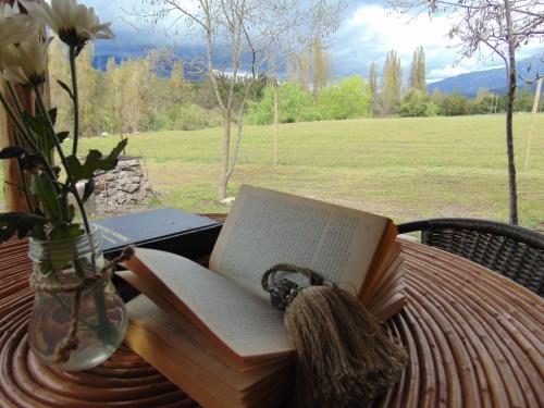 an open book on a table with a vase of flowers at Cabañas Puente Negro in Puente Negro