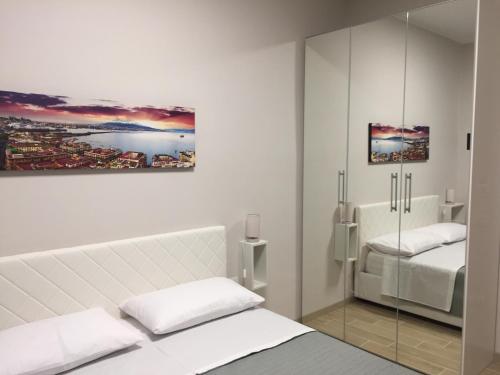 ein weißes Schlafzimmer mit einem Bett und einem Spiegel in der Unterkunft Villa Augustea in Somma Vesuviana