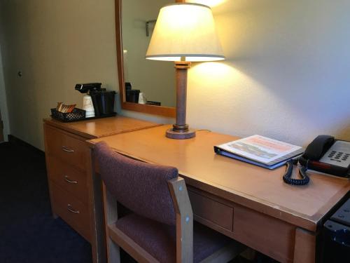 a desk in a hotel room with a lamp and a telephone at Shelikof Lodge in Kodiak