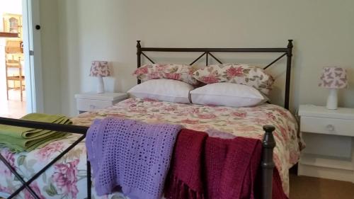 The Manager's Cottage في Grove: غرفة نوم مع سرير مع الوسائد الأرجوانية والوردية