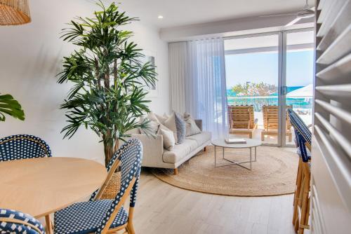 a living room with a table and chairs and a couch at Tingirana Noosa in Noosa Heads