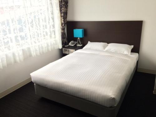 Un dormitorio con una gran cama blanca y una ventana en Libest Inn Amami en Setouchi