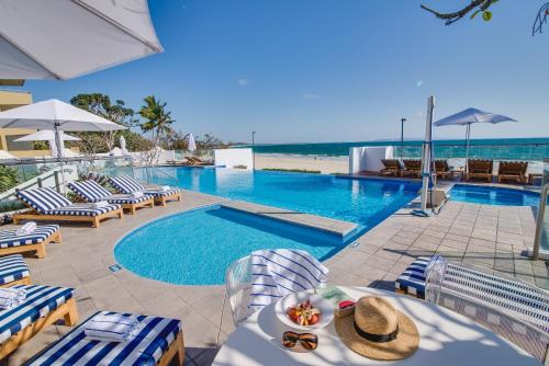 a pool with chairs and a table and a swimming pool at Tingirana Noosa in Noosa Heads