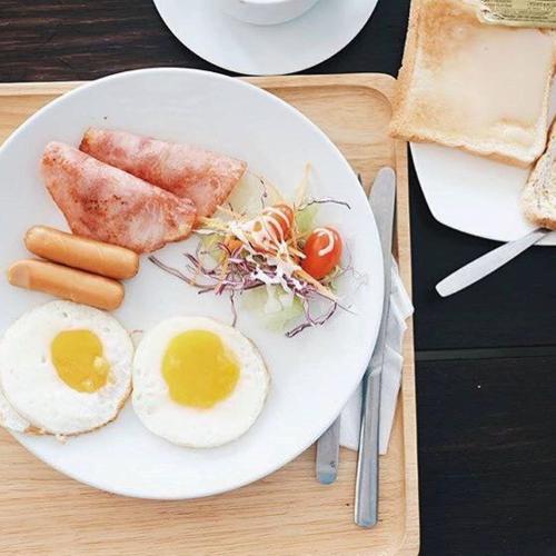 a plate of breakfast food with eggs sausage and tomatoes at Siambeach Resort in Cha Am