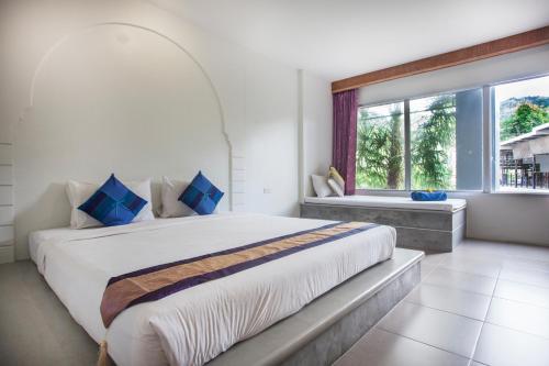 a bedroom with a large bed and a window at Dinar Lodge in Bang Tao Beach