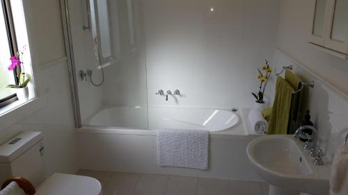 een witte badkamer met een bad en een wastafel bij The Manager's Cottage in Grove