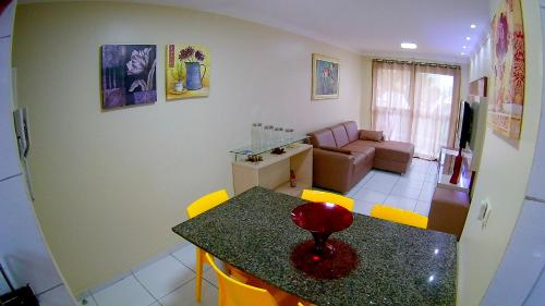 a kitchen and living room with a table and yellow chairs at Porto Dreams Flat in Porto De Galinhas
