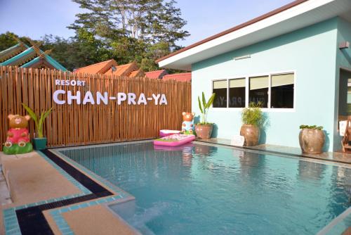 a swimming pool in front of a house with a fence at Chanpraya Resort in Chanthaburi