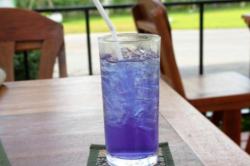 a glass of purple liquid sitting on a wooden table at Chanpraya Resort in Chanthaburi